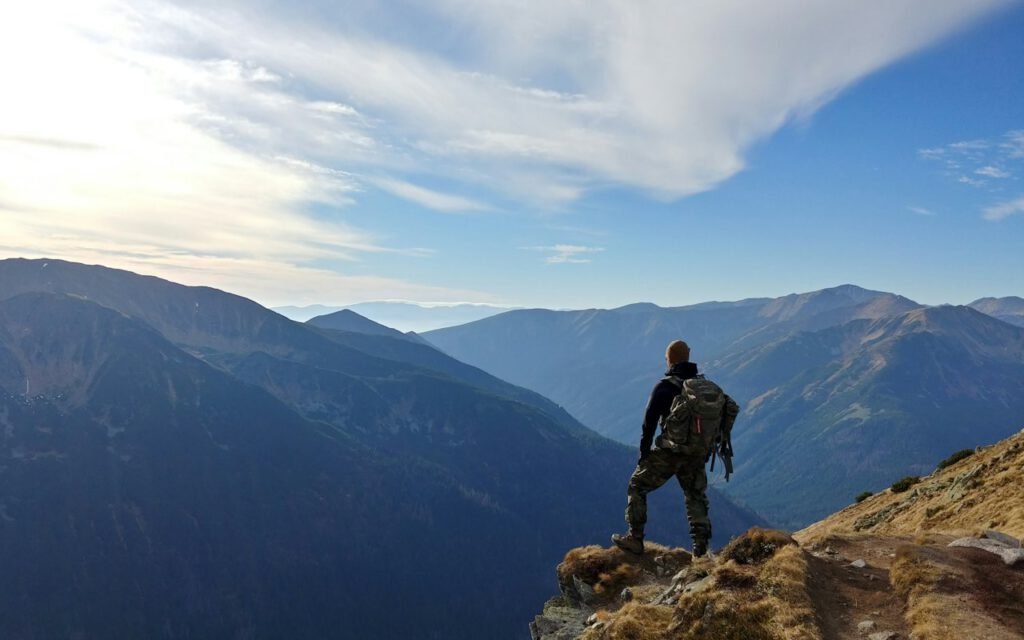 Hiker on a mountain trail looking toward distant peaks