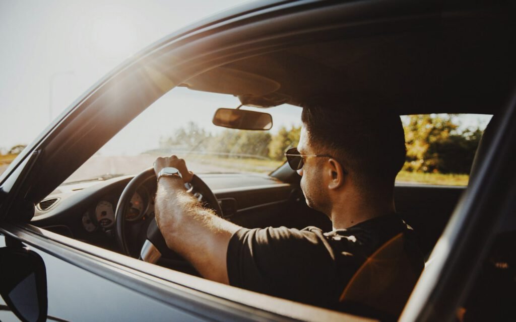 A driver seen through the side window of a car