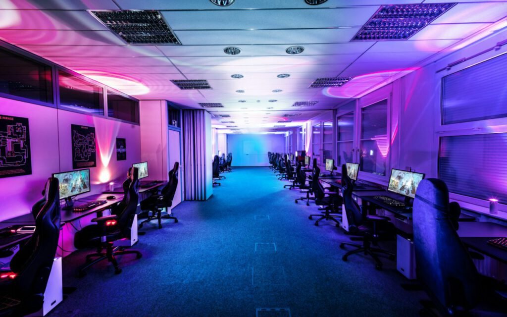 A room lined with gaming computers and colorful lighting