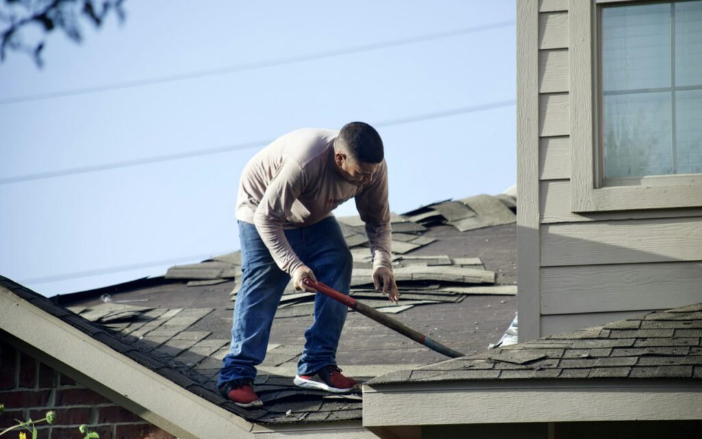A worker repairing shingles on a house roof