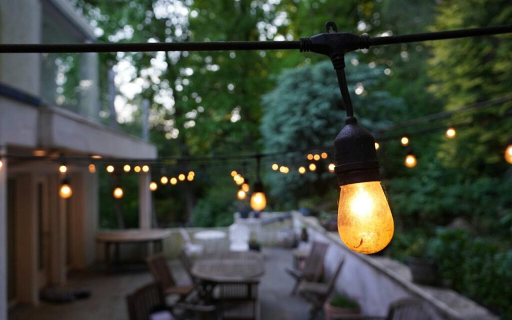 A backyard patio glowing with string lights at dusk