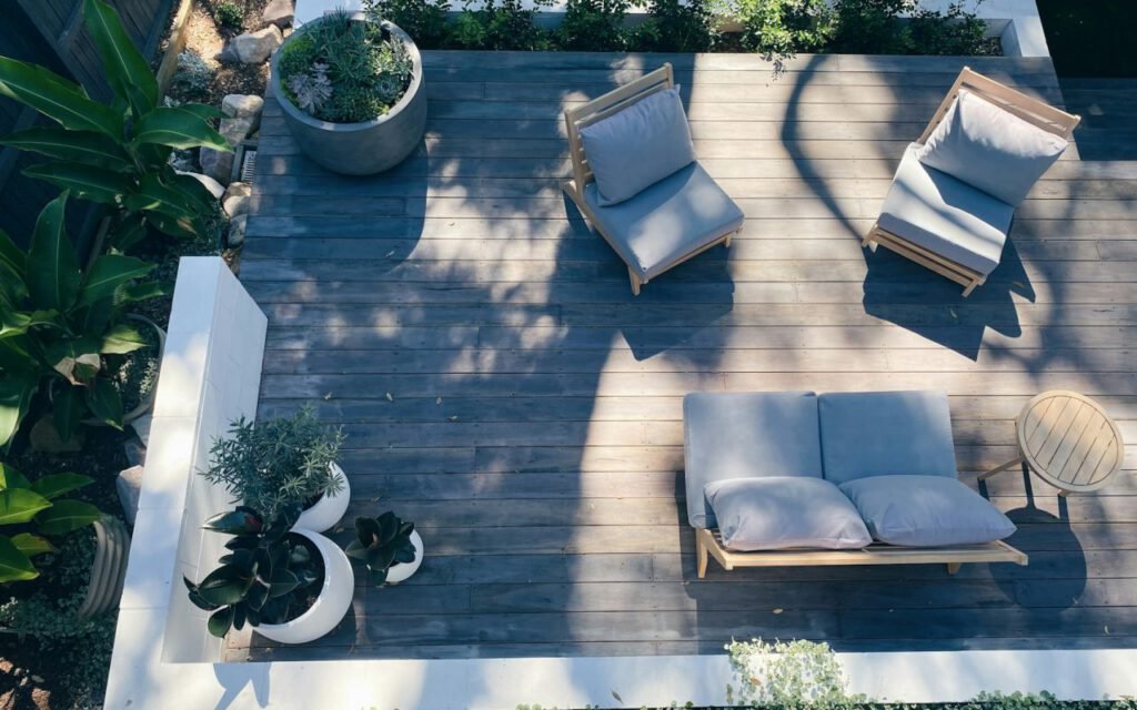 A wooden backyard deck with shrubs planted along its edge