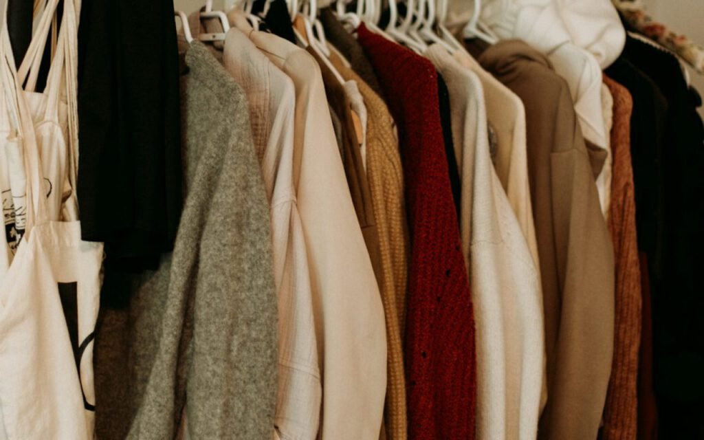 A neatly organized closet with folded sweaters and hanging clothes