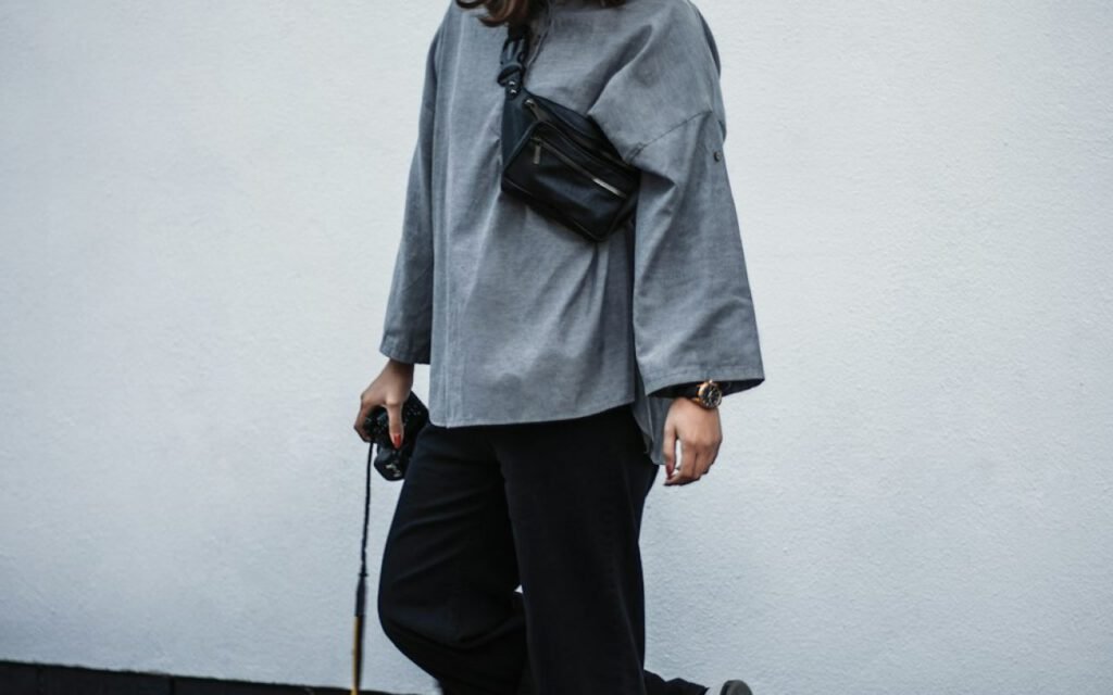A woman walking down a city street in a neutral coat and jeans
