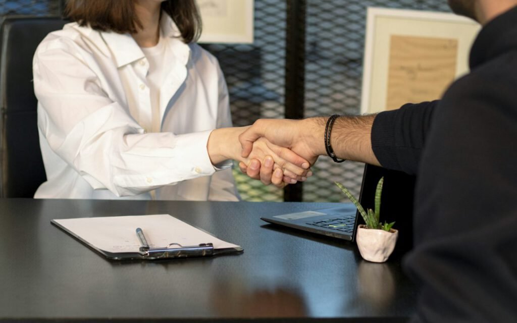 Two people shaking hands across a desk