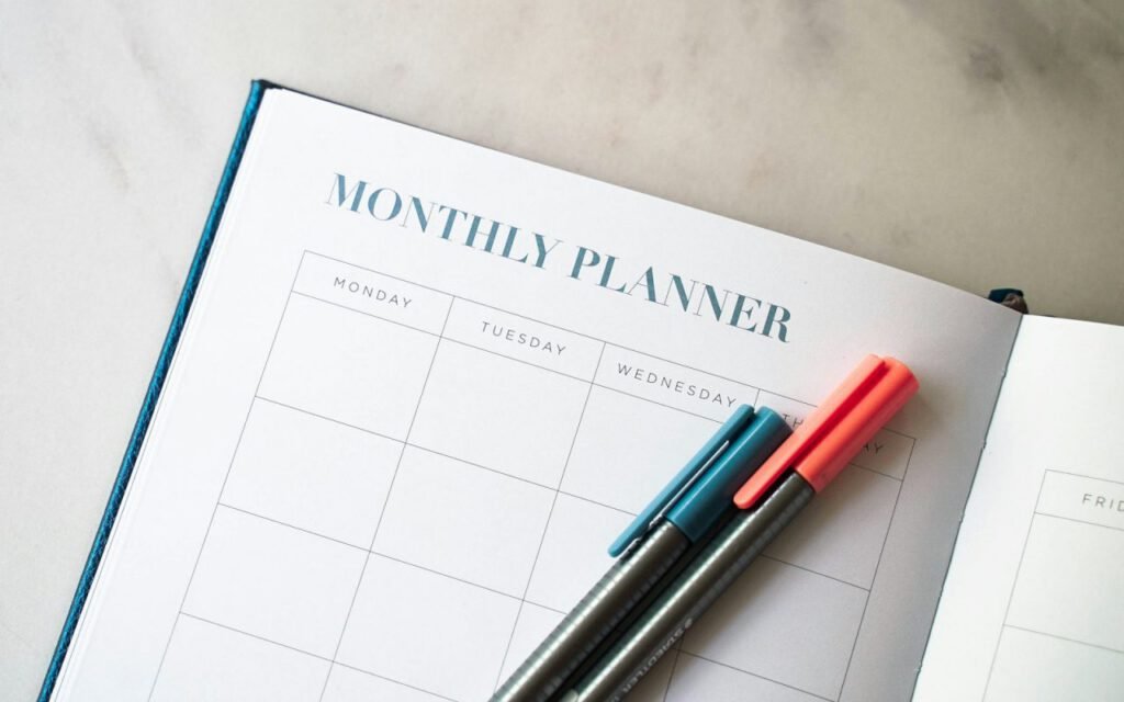 A monthly planner and pen on a desk for tracking bills