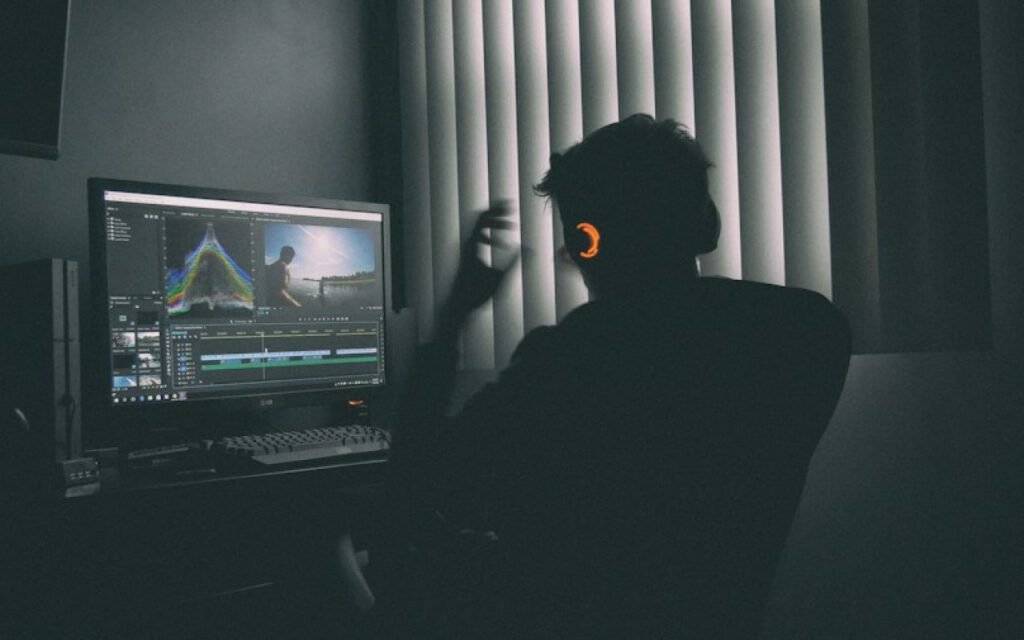 A person editing video at a computer in a dark room