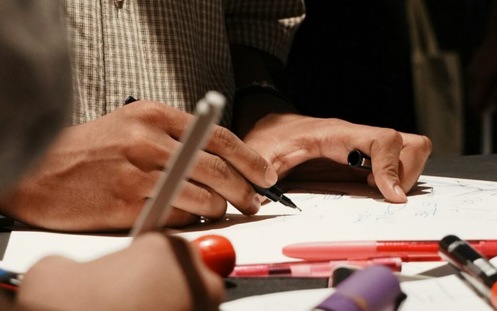 An illustrator's hands sketching on paper with a pencil