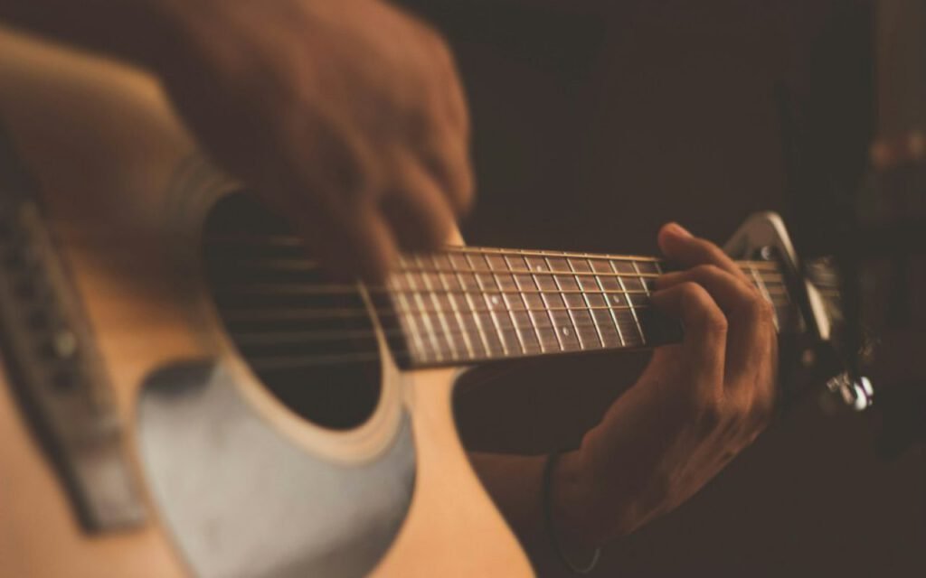 Hands playing an acoustic guitar