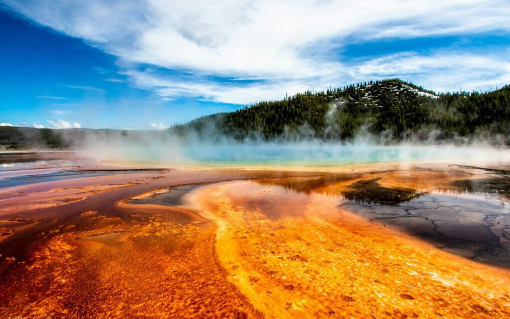 Steam rising from a colorful geothermal pool in a national park