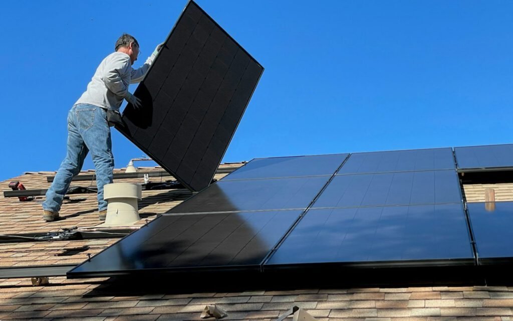 A solar installer fitting a panel onto a residential roof