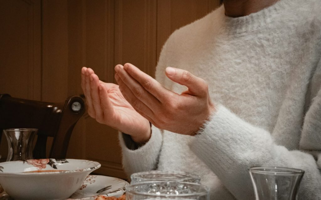 Hands raised in prayer before an iftar meal