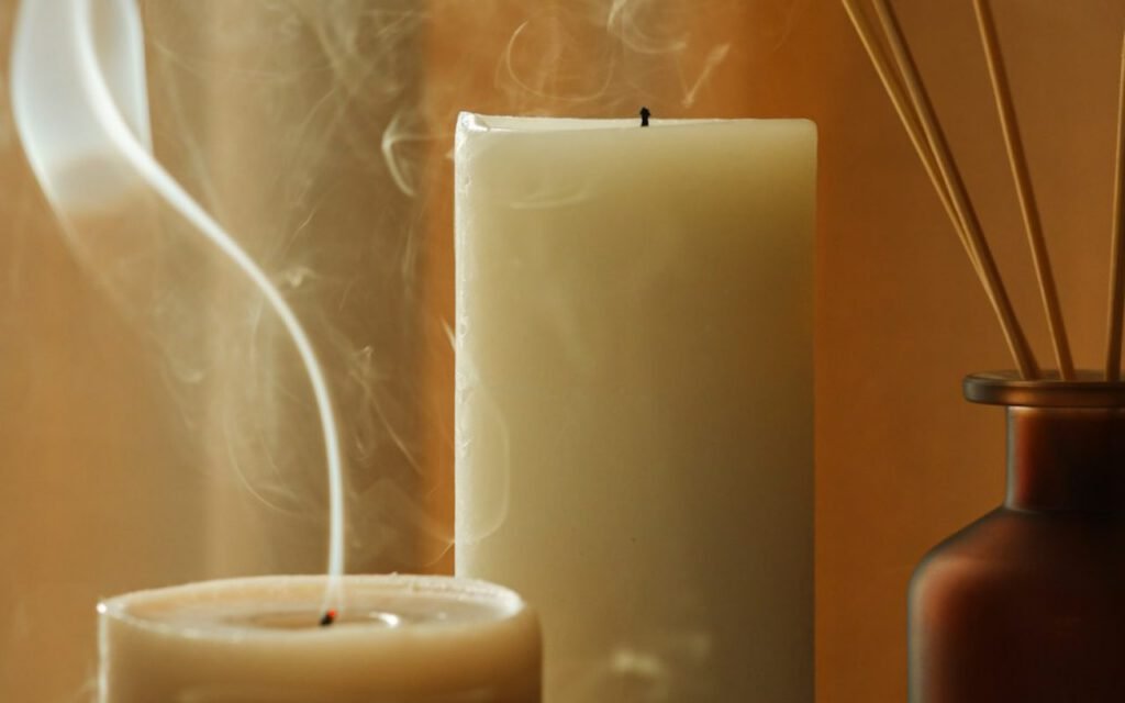 Hand-poured candles in glass jars lined up on a wooden table