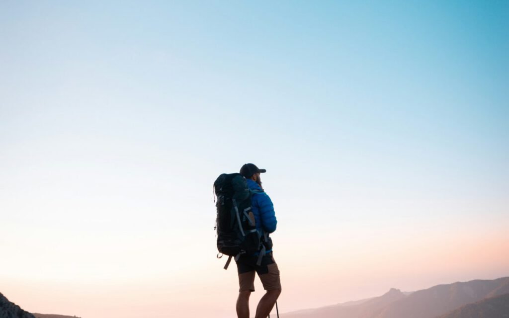 A hiker walking along a narrow mountain trail on a clear day