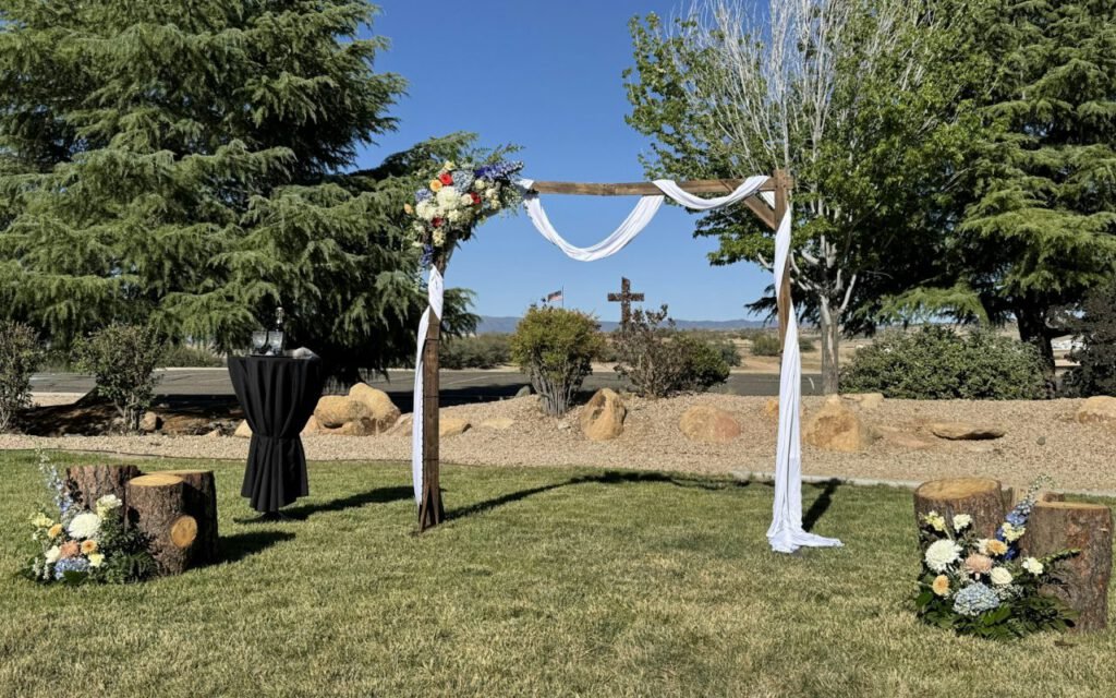 A floral ceremony arch set up on a green lawn