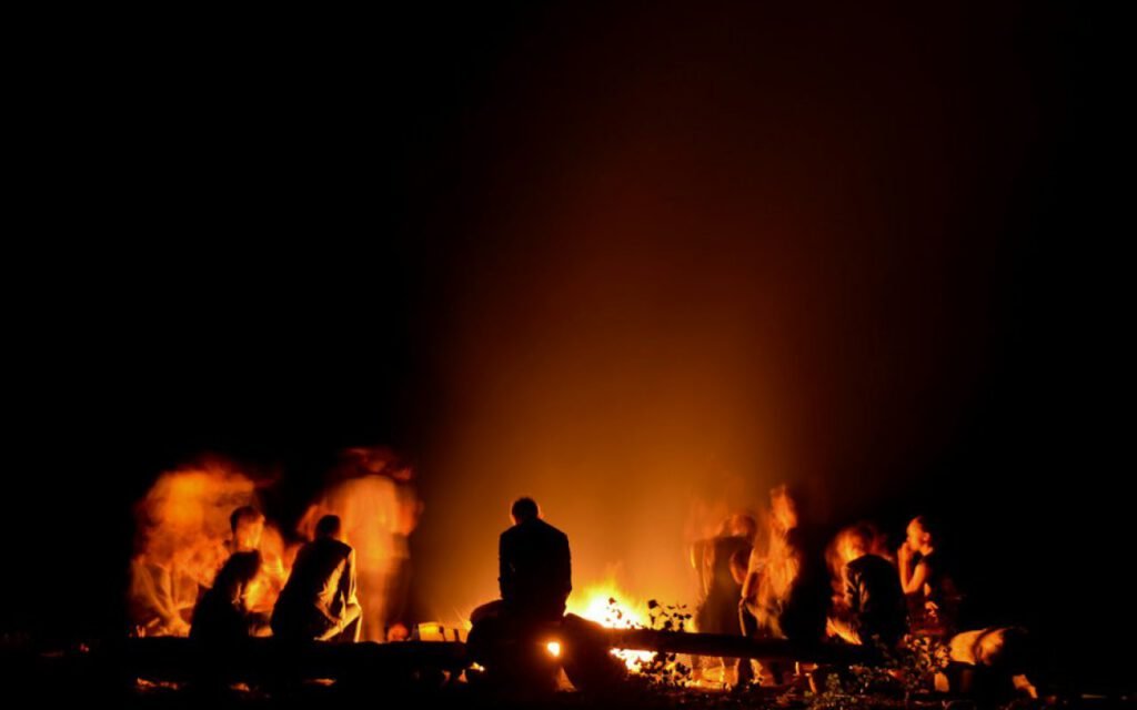 Friends gathered around a campfire at dusk